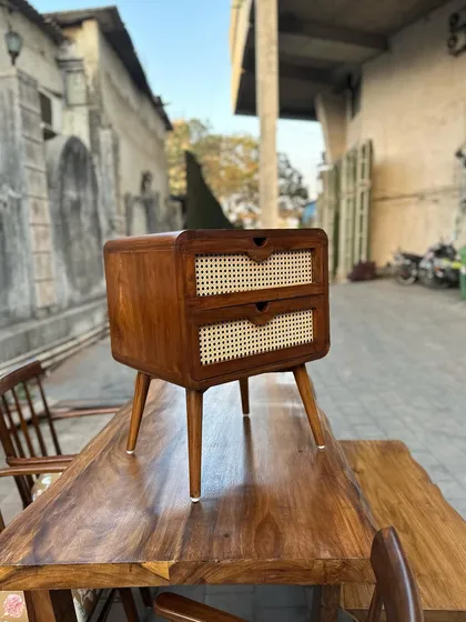 A mid-century modern nightstand with caned drawers, placed on top of a live-edge table to show its versatility.