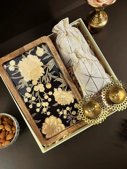 The 'Diwali Dazzle' hamper is all about elegance. It features a stunning floral tray paired with decorative diyas and a potli of almonds.