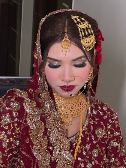 A close-up of the bride's makeup, featuring a bold ombre lip, smokey eyes, and a flawless base. The red rose in her hair adds a romantic touch.
