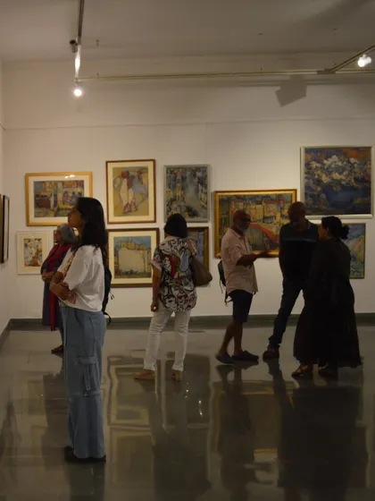 A wide shot of the gallery during the Vidya Bhushan preview, showing a diverse group of visitors.
