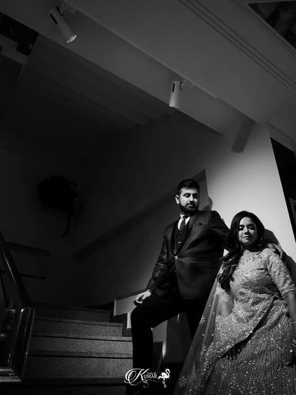 A low-angle black and white shot of a couple on a staircase, using shadows and perspective for a dramatic and imposing portrait.