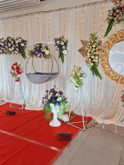 A side angle showing the arrangement of the floral stands and the hanging cradle against the fairy light backdrop.