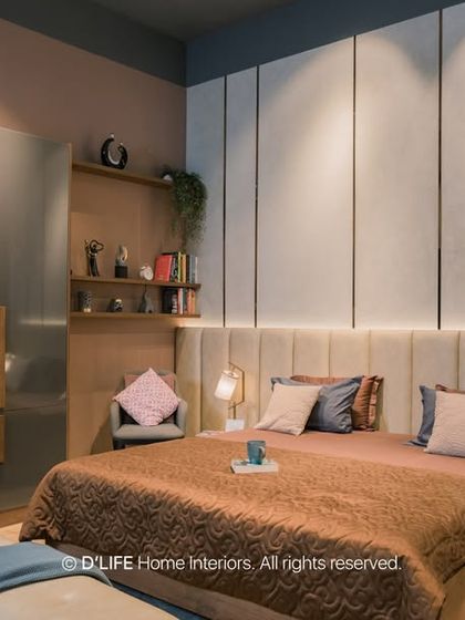 A luxurious bedroom design with a floor-to-ceiling upholstered headboard and integrated backlighting. The glossy grey wardrobe and rich textiles create a sophisticated and restful ambiance.