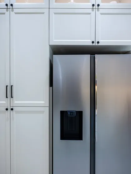 A close-up of the cabinetry built around the refrigerator. The clean lines and matching hardware ensure that the storage feels fully integrated, creating a polished and cohesive look.