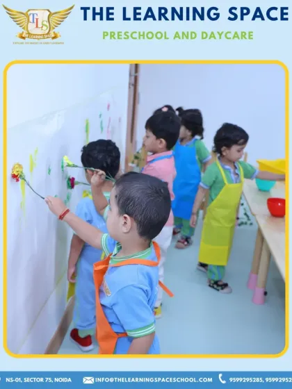 Little artists at work on a wall mural. This activity encourages gross motor skills and teamwork, turning a simple wall into a collective masterpiece.
