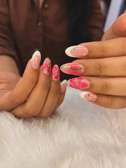 A beautiful floral design with a classic French tip. This look combines a white tip with hand-painted pink flowers and delicate gold accents for a romantic feel.