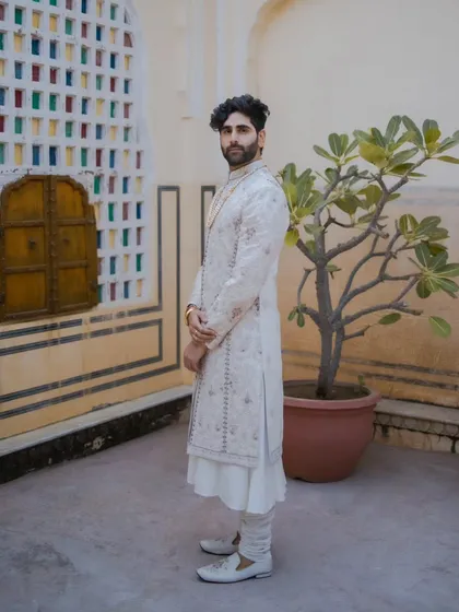 A full-length groom portrait showcasing his style against a classic Jaipur backdrop. The colorful stained-glass window adds a touch of heritage to this modern, elegant shot.