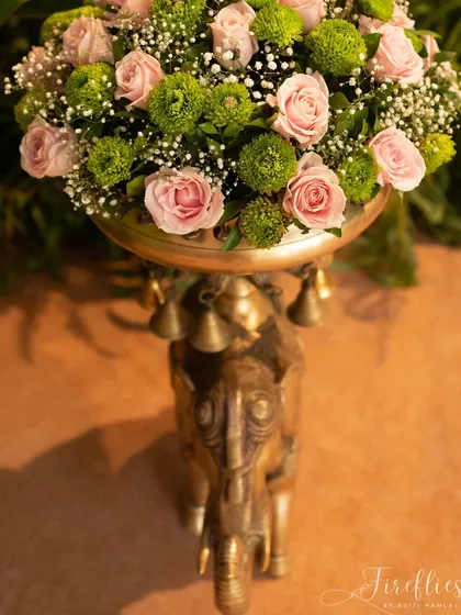 A close-up of a traditional brass elephant stand holding a beautiful floral arrangement, a classic element of auspicious Indian decor.