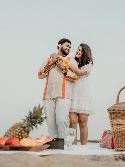 The couple shares a hug during their beach picnic. This photo captures the beautiful setup and their loving interaction in a single frame.