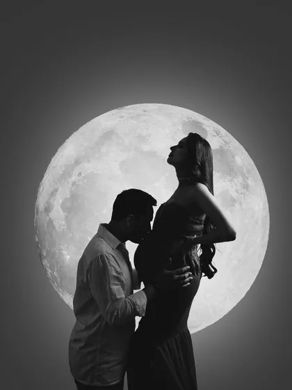 A love story written in the stars. This black and white moon silhouette is incredibly romantic and powerful. The mother-to-be's elegant pose and his gentle kiss create a timeless work of art.
