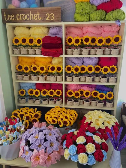 My favorite corner of the workshop, featuring shelves neatly organized with potted sunflowers and various yarn colors.