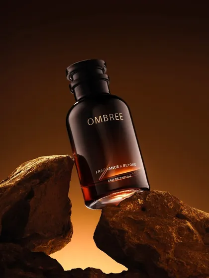 An earthy and rugged shot of a perfume bottle nestled between rocks. The warm, directional lighting and natural textures are perfect for a woody or spicy fragrance.