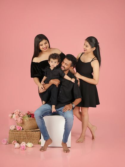 The smallest moments can be the most beautiful. This lovely family portrait against a soft pink background is full of warmth and affection.