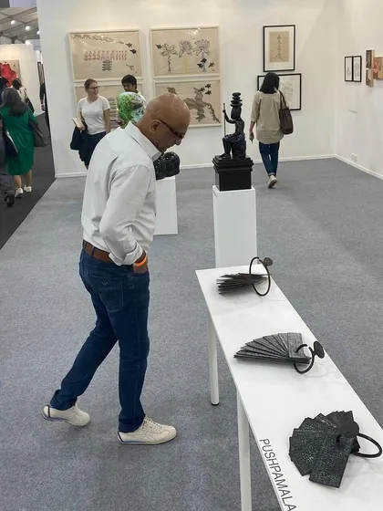 A visitor examining the 'Atlas' series of copper sculptures by Pushpamala N.