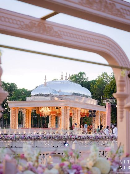 The 'Saanjh Niwas' mandap, framed by lush florals and a waterbody we created from scratch. This view showcases how we blend grand architecture with natural elements for a harmonious design.