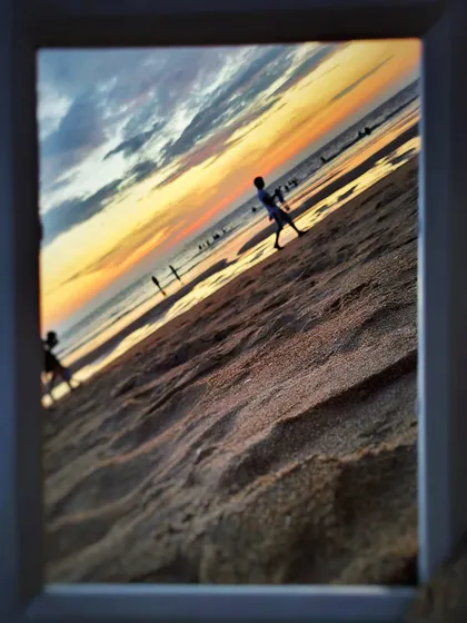 A frame within a frame. This photo uses a physical picture frame to capture the beach at sunset, creating an interesting composition and a sense of looking at a memory.