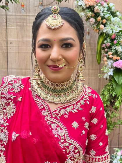 A beautiful close-up portrait of the bride. Her makeup is flawless, with a traditional nath and maang tikka completing her classic bridal look.