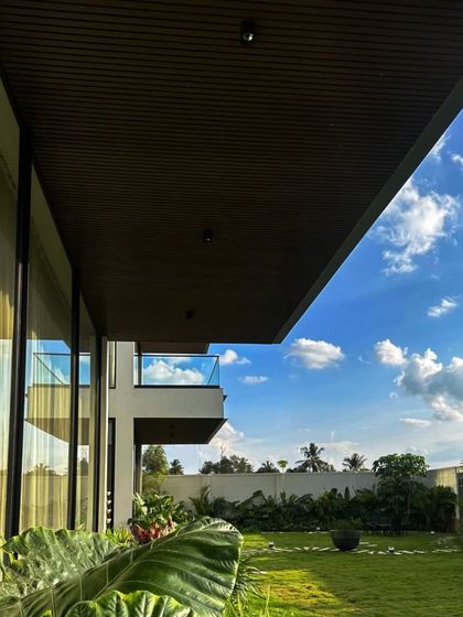 A view from the patio of a villa we designed, showing how the garden becomes an extension of the home. The large glass windows reflect the sky and the lush greenery we planted.