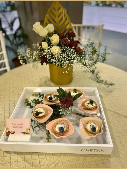 White Chocolate Blueberry Tarts presented in a branded Chetak tray. The delicate pastry and creamy filling make for an elegant bite-sized dessert.