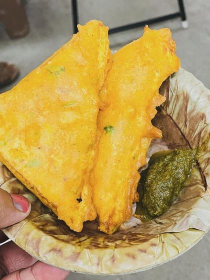 A classic rainy-day snack: bread pakoda. Here you can see two crispy, golden-fried bread pakodas served on a leaf plate with our homemade green chutney.