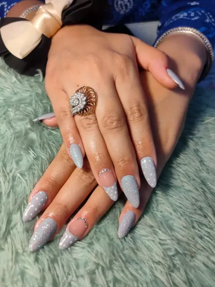 A simple yet stunning design featuring stiletto nails with a textured, light grey glitter polish. The negative space and rhinestone details on the accent nails add a modern touch.