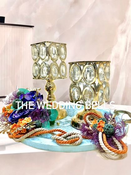 A beautiful Diwali hamper featuring crystal candle holders and floral arrangements on a painted wooden base.