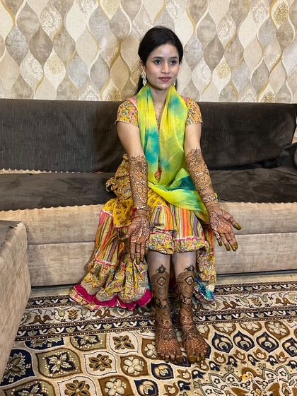A full-length photo of a happy bride, showing her complete hand and leg mehndi.