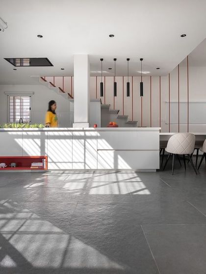 The open-plan kitchen and dining area is designed for connection. The long dining table extends from the kitchen island, creating a central hub for cooking, eating, and socializing, all while being bathed in natural light from the adjacent courtyard.