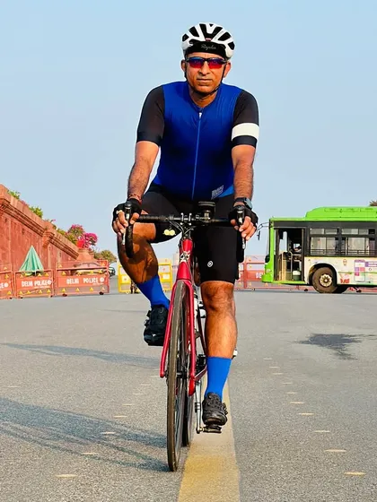 A rider on his red Colnago bike, riding down the center line of an empty road.