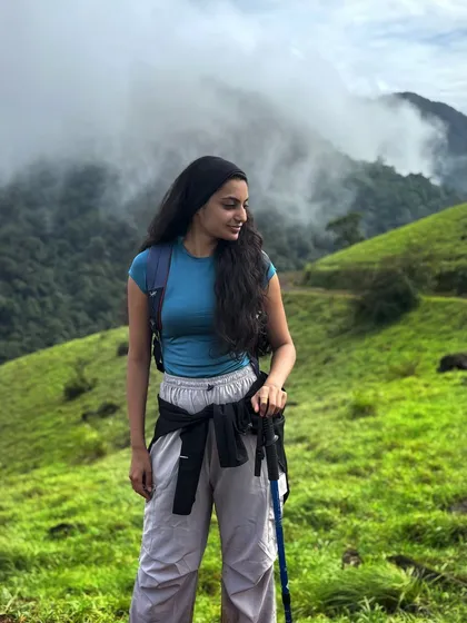 A trekker with her hiking pole, enjoying the green and misty views of Kodachadri.