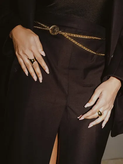 A detailed shot from a session with Malavika Mohanan, focusing on the styling. The image highlights the intricate gold chain belt and rings, capturing the high-fashion aesthetic of the look.