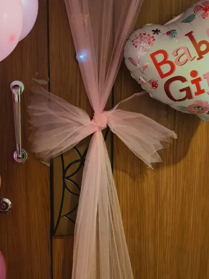 A close-up of the door decoration, showing the beautiful combination of the pink tulle bow and the "Baby Girl" foil balloon.