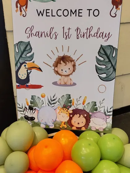 A close-up of the welcome sign for Shanil's jungle-themed first birthday. The sign features adorable illustrations of a lion, toucan, and other animals, perfectly matching the party's decor.