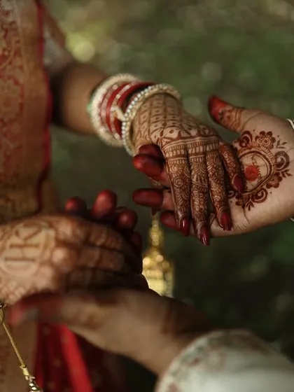A close-up of the couple's hands during the ceremony. This shot highlights the bride's henna and bangles, capturing a moment of connection and tradition.