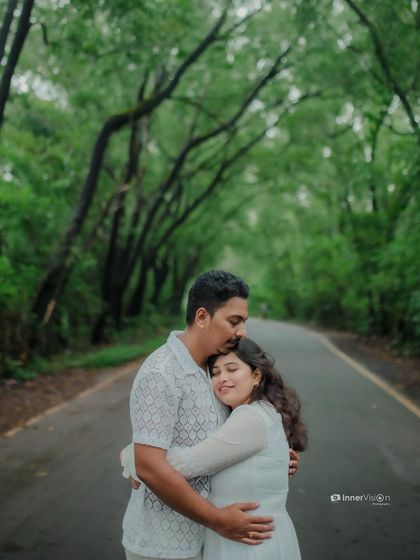A comforting hug from behind on a road surrounded by lush greenery. This photo captures a sense of security and deep affection between the couple.