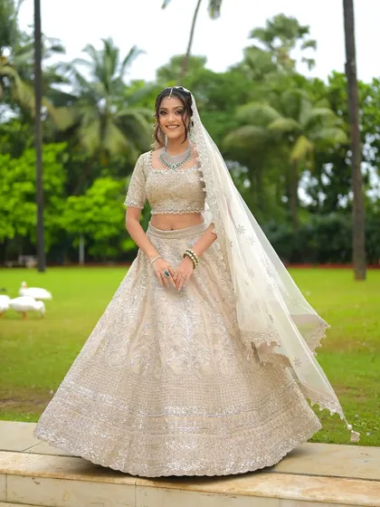 A beautiful outdoor shot showcasing the entire modern bridal look. The long veil and intricate lehenga are perfectly balanced with understated hair and makeup.