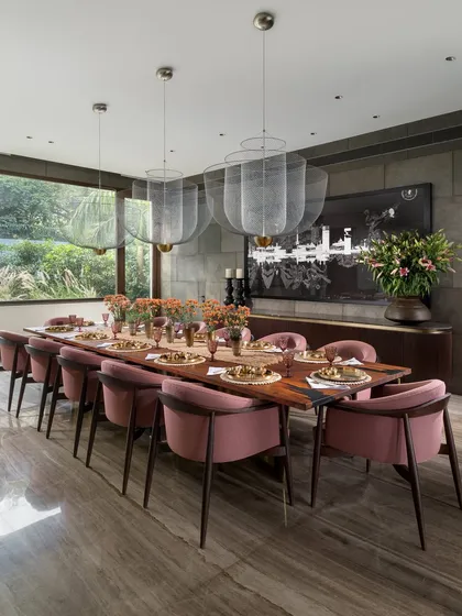 A dining room should be a place for memorable gatherings. For this space, I chose dusty pink chairs to add a touch of warmth and personality against the stone-clad walls. The solid wood table with its dancing brass base and the ethereal Meshmatics Chandeliers create an ambience that is both elegant and inviting.