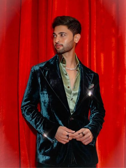 Jainam Vora in our deep green velvet tuxedo, a perfect pick that brings together sophistication and style against a dramatic red backdrop.