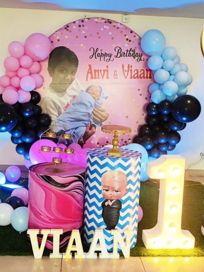 A joint 10th and 1st birthday celebration with a K-Pop and Boss Baby theme. The decor features a Blackpink cutout, a Boss Baby plinth, and large light-up numbers.