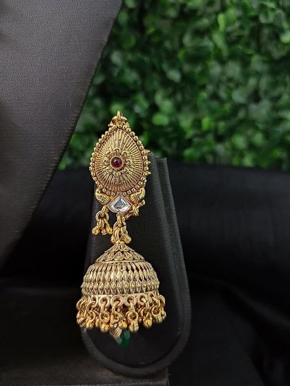 An antique-finish jhumka with intricate carving details, perfect for a classic look.