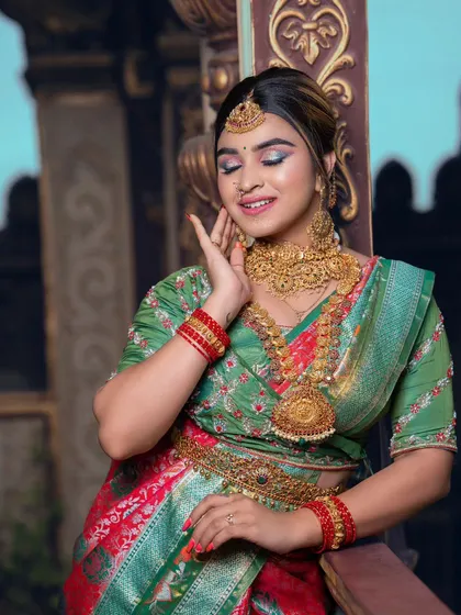 A close-up of a student's work, showing a happy bride with a green and red saree. The makeup is fresh and dewy.