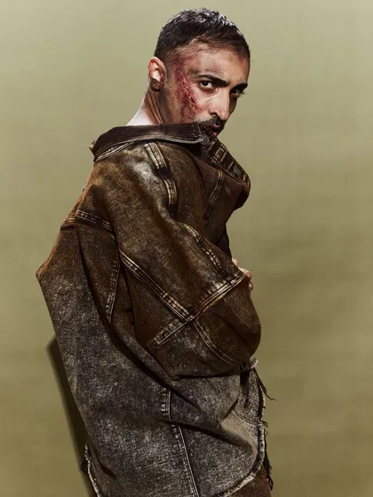 A striking portrait of a model in a distressed, oversized denim jacket for the Huemn show.