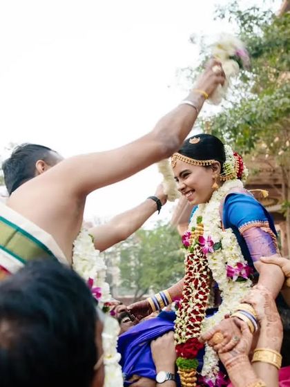 A joyful ritual from a Tamil wedding where the bride and groom are lifted up by their families to exchange garlands.