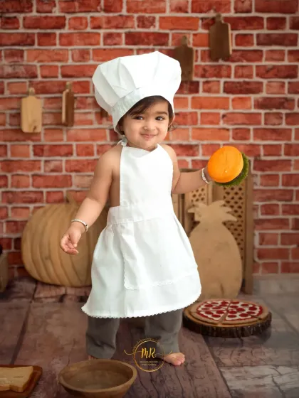 Our 'Little Chef' stands proudly in his apron and hat, holding a toy burger in the kitchen-themed set.