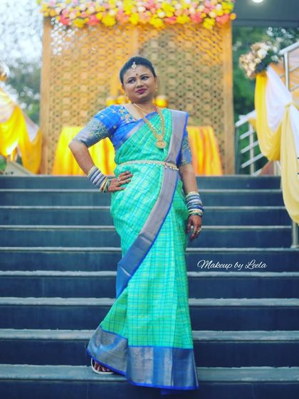 A confident pose from a client at a wedding event. Her turquoise and blue saree is paired with bold makeup and traditional jewelry for a striking look.
