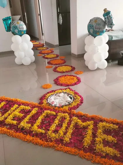 This welcome home decoration combines a traditional flower pathway with modern balloon pillars topped with 'It's a Boy' foil balloons.