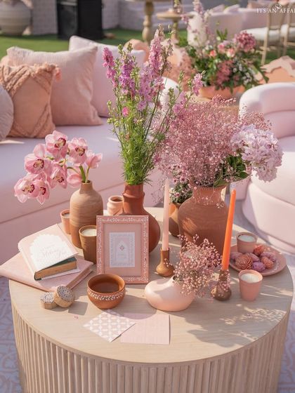 A coffee table styled with pink florals, custom stationery, and terracotta accents, perfectly capturing the 'Handpainted Story' theme.