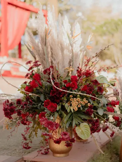 A stunning floral installation featuring pampas grass and rich red blooms. This arrangement was part of the 'Regal Rustic Reverie' decor, adding texture and drama to the entrance.