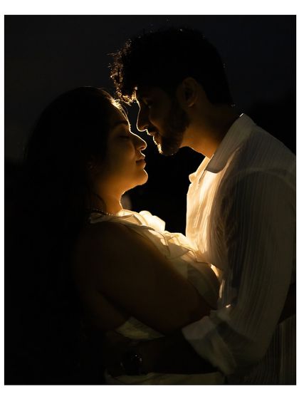 A beautifully backlit silhouette of the couple about to kiss. The light outlines their profiles, creating a romantic and intimate portrait against the darkness.