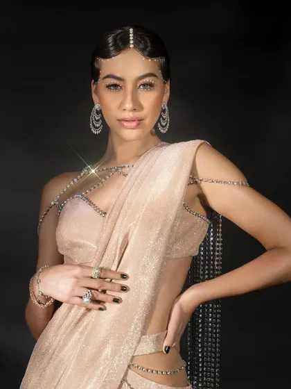 A detailed close-up from the Nikhil Thampi campaign. This image highlights the craftsmanship of the jewelry and the shimmering fabric, with a direct and engaging look from the model.